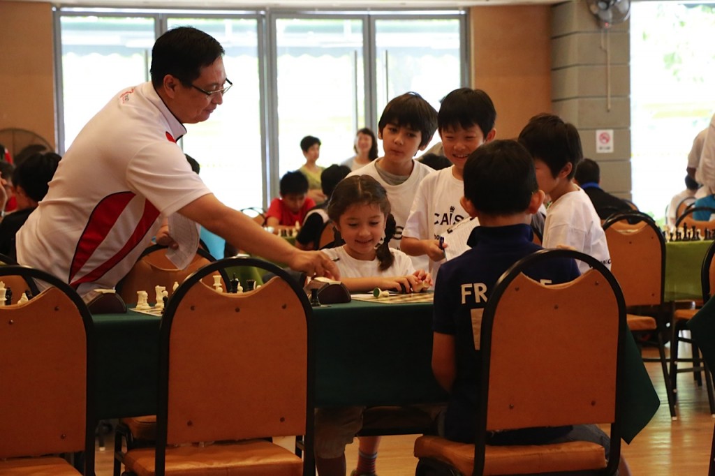Caissa U10 team members gather with interest  around Mei Jing's board after winning her game.